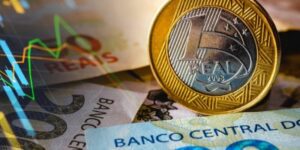 Imagem de reais e moedas brasileiras ao lado de uma seta em alusão aos investimentos no país