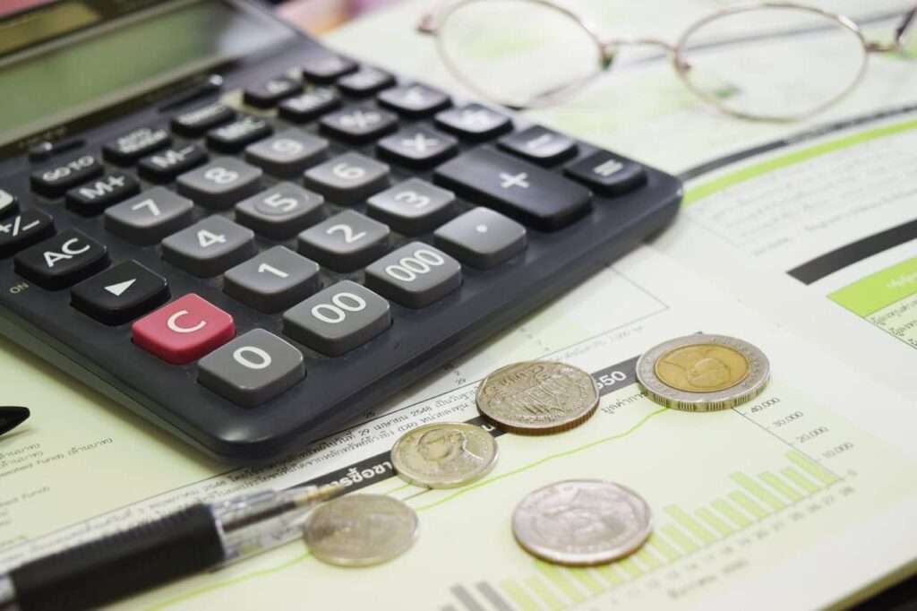 Imagem representando a taxa de juros, mostrando uma calculadora junto a moedas.