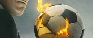 Homem segura bola de futebol pegando fogo; enquadramento mostra apenas seu queixo