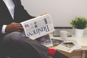 Imagem representando o Boletim Focus, mostrando um profissional lendo um jornal com notícias financeiras.
