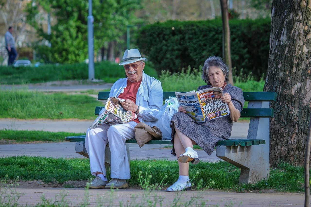 Imagem com dois idosos sentados em um banco representando como declarar aposentadoria no Imposto de Renda (IR).