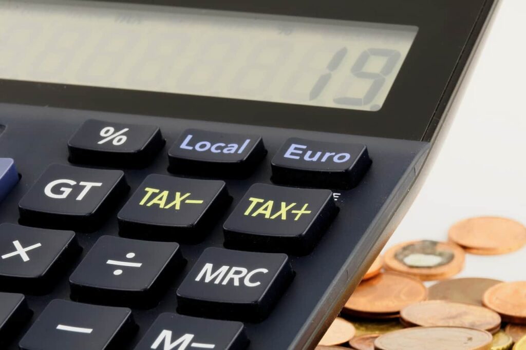 Imagem de uma calculadora com moedas para representar como declarar poupança no imposto de renda (IR).
