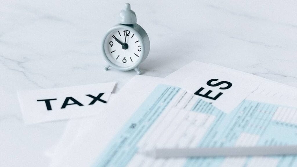 Imagem com um relógio e papéis representando como declarar renda fixa no imposto de renda (IR).