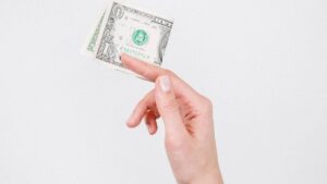 Imagem de uma mão segurando uma nota de um dólar para representar a tributação de dividendos.