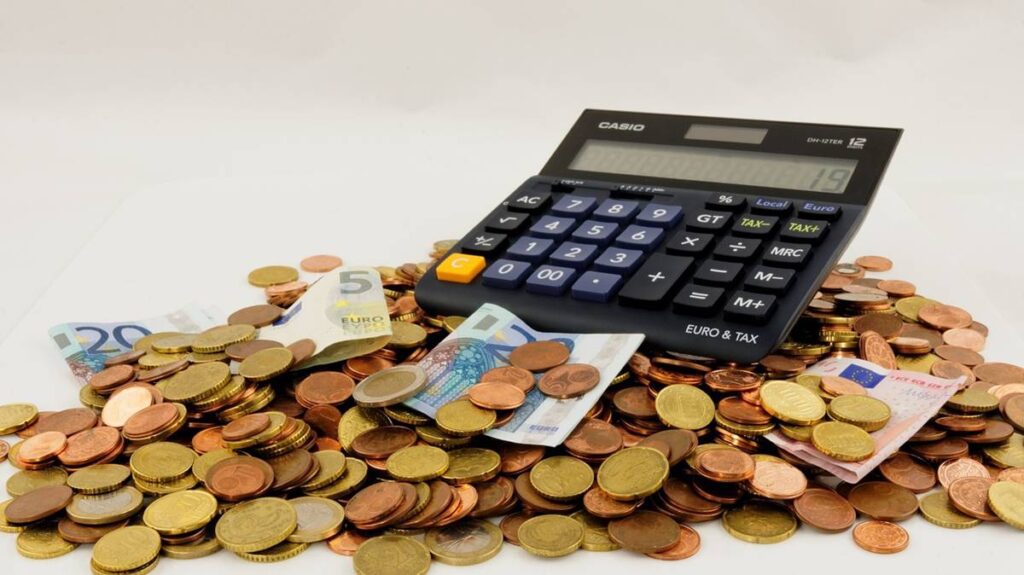 Imagem com moedas e uma calculadora para representar a tributação de opções.