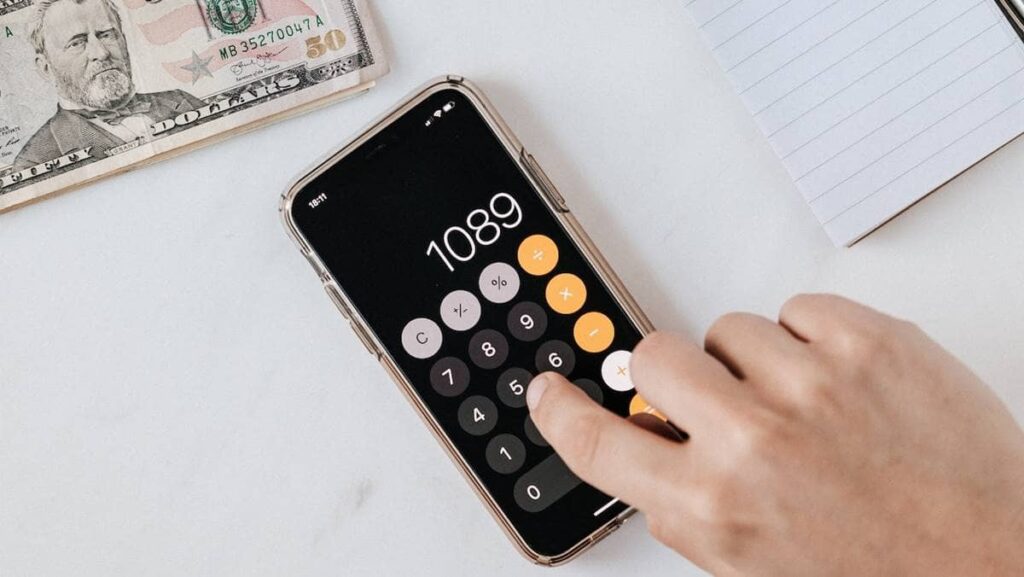 Imagem contendo um celular com a tela aberta em uma calculadora para representar a tributação dos BDRs.