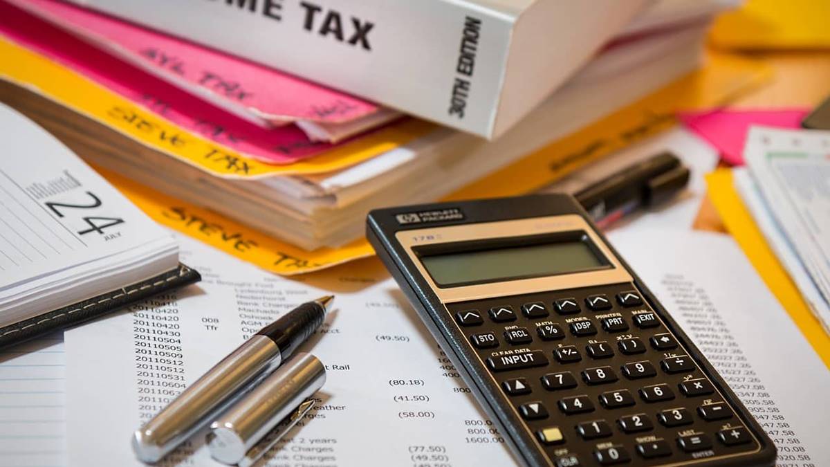 Imagem com uma calculadora e contas no papel para representar a tributação dos ETFs.