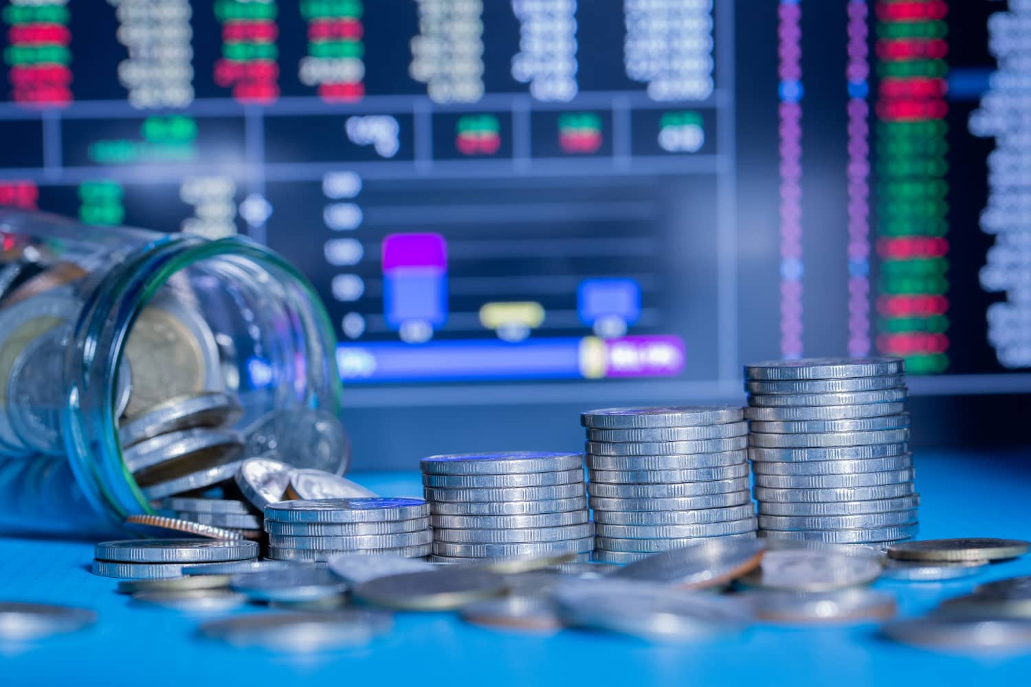Imagem com moedas e m gráfico ao fundo para representar a tributação de fundos de investimento.
